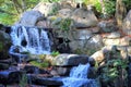 Small rocky waterfall in a woodland glade with sunlight streaming through