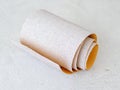 Small roll of extra coarse aluminum oxide sandpaper on a white rough textured background. Abrasive paper for dry sanding. Royalty Free Stock Photo