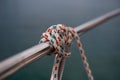 Small rope knot tied around silver metal rod. Close up of a knot