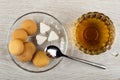 Small biscuits, piece of sugar in shape heart in saucer, spoon, cup of tea on wooden table. Top view Royalty Free Stock Photo