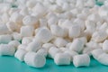 Small round white marshmallows on a aquamarine backgrouns.