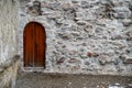 Small Rounded Wooden Medieval Middle Ages Door in Ancient Stone Wall on the Street with Copy Space Royalty Free Stock Photo