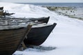 Small row boat laying on a pebble beach covered in snow Royalty Free Stock Photo