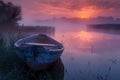 A small rowboat gently docked on the edge of an ancient lake, surrounded by tall grass and reeds under a vibrant sunrise Royalty Free Stock Photo