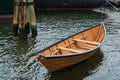 Small rowboat tied up beside a larger sailing vessel and dolphin pier