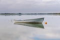 Small rowing boat, anchored on a lake, Gray sky