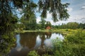 A small rural brown house by a pond surrounded by greenery. Beautiful rural landscape. Roztocze, Poland