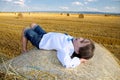 small rural girl on the straw after harvest field with straw bales Royalty Free Stock Photo