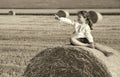 small rural girl on the straw after harvest field with straw bales Royalty Free Stock Photo