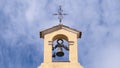 Small rural village church detail. Bell tower and a cross against a blue sky. Empty copy space