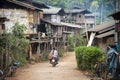 A small rural village, a hill tribe village in Chiang Mai Thailand, houses made of wood and bamboo, and a dirt road with a