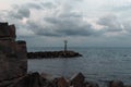 Small rusty lighthouse dark clouds scenery seen through rocks winter time greece Royalty Free Stock Photo