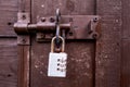 Small rusty metal code padlock on a metal latch and dark brown wooden door. Property safety and protection concept. Security Royalty Free Stock Photo