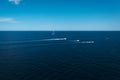 Small sailboat and motor boats travel through the blue sea horizon, background. Royalty Free Stock Photo