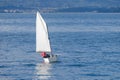 small sailboat is in the water with a young yachtsman in a red life jacket Royalty Free Stock Photo