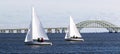 Two two person sailboats sailing toward West Islip with the Great South Bay bridge Royalty Free Stock Photo
