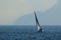 Small sailing ship on the sea surrounded by mountains covered in the fog at daytime Royalty Free Stock Photo