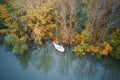 Small sailing yacht and lots of green and yellow trees, autumn, view from the height Royalty Free Stock Photo