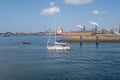 Small sailing yacht sails out of IJmuiden seaport towards the No