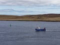 A small Salmon Fishing Boat with a small Aft Crane heads out of Bressay Sound in calm water after a Winters storm.
