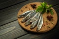 A small salted anchovy or sprat with spices and herbs on a wooden serving board. The idea of a fish diet Royalty Free Stock Photo