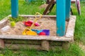 A small sandbox in a wooden structure made of boards. Children\'s toys for playing in the sand. Royalty Free Stock Photo
