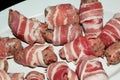 Small sausages, pigs in blankets, wrapped in bacon strips ready to cook.