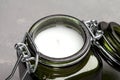 A small scented candle in a green glass candlestick with a tight lid. Paraffin and vegetable wax. Isolated on gray background