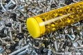 Close-up of metal screws in transparent box on texture from a pile of small silvery bolts