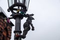 Small sculpture of bronze gnome lamplighter on street lantern at Wroclaw