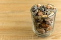 Small sea stones in a glass vessel. The idea of decorating the house with small rocks in a jar on a wooden blurred background Royalty Free Stock Photo