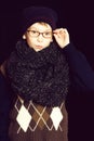 Small serious boy or cute nerd kid in glasses, hat and fashionable knitted scarf on black backgroun