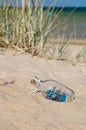 Small ship in the glass bottle lying on the beach Royalty Free Stock Photo