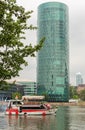 A small ship on the river. Frankfurt am Main. River transport. Round and glass tower above the water.