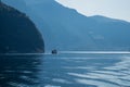 Small ship sails in blue water with large mountais. Norway landscape, fjord cruise. Royalty Free Stock Photo
