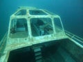 Small ship wreck sits partially submerged in tranquil, crystal-clear waters