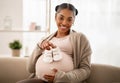 Pregnant black woman holding small baby shoes relaxing at home Royalty Free Stock Photo