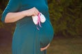 Small shoes for the unborn baby in the belly of pregnant woman. Pregnant woman holding small baby shoes relaxing at home in Royalty Free Stock Photo