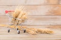 A small shopping cart full of ripe wheat ears and a handful of wheat ears next to it Royalty Free Stock Photo