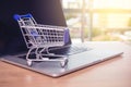 Small shopping cart on Laptop for shopping online with sunny background, Technology business online concept. Royalty Free Stock Photo