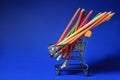 Small shopping cart with pencils on color background Royalty Free Stock Photo