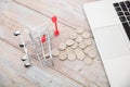 Small shopping carts toppling over the table and dollar coins being sucked away by laptops