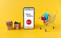 A small shopping trolley, boxes, packages and a mobile phone on a yellow background. Online shopping concept, side view Royalty Free Stock Photo