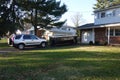 A small short beat up black and white dumpster containing wood debris seen in a driveway in front of a garage door