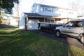 A small short beat up black and white dumpster containing wood debris seen in a driveway in front of a garage door