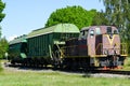 A small shunting diesel locomotive pulls two bulk wagons