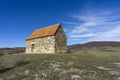 Small shurch on the rock. Wooden door. Orange tiled roof, stone walls. Green grass and bushes. Bright blue sly with clouds. Royalty Free Stock Photo