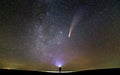 Small silhouette of a scientist with flashlight on his head pointing bright beam of light on starry sky with C/2020 F3 NEOWISE Royalty Free Stock Photo