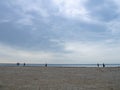 Small silhouettes of people on the shore. People in the distance stand and look at the sea. Overcast weather. Out of season at the Royalty Free Stock Photo