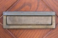 Small silver door mailbox on wooden doors. Small letterbox